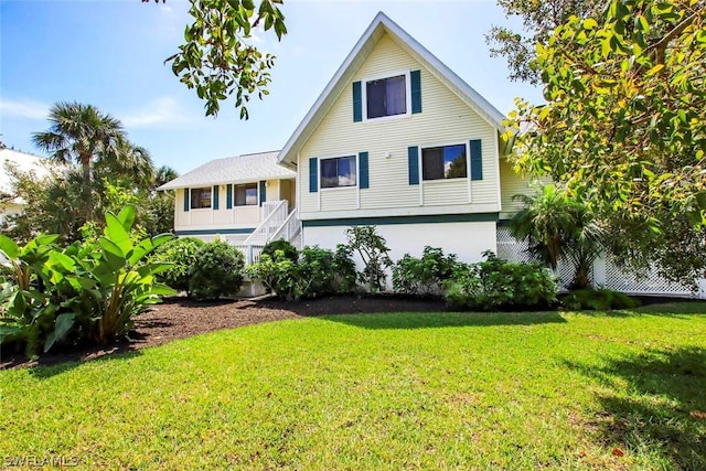 back of property with stucco siding, a lawn, and stairs