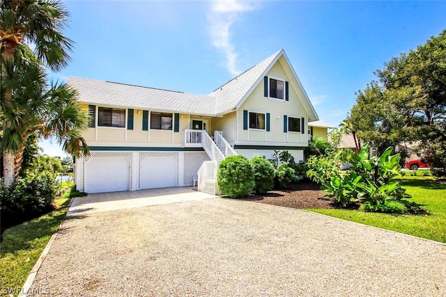 view of front of property featuring stairway, a garage, and driveway