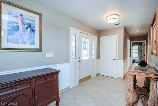 foyer featuring a wealth of natural light, visible vents, a wainscoted wall, and light tile patterned floors