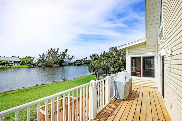 wooden deck featuring area for grilling, a lawn, and a water view