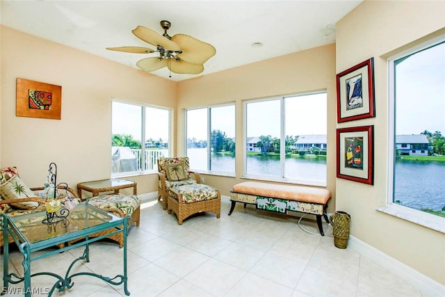 sunroom / solarium with a ceiling fan and a water view