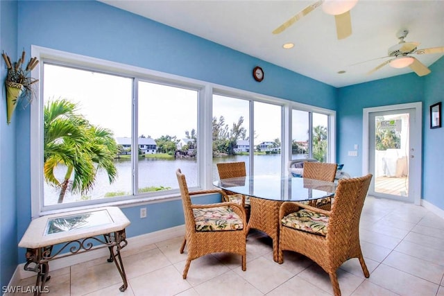 sunroom with a ceiling fan and a water view