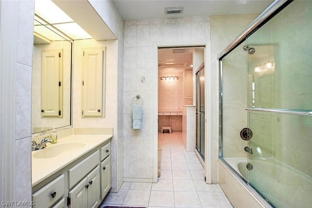 bathroom with vanity, visible vents, shower / bath combination with glass door, tile walls, and tile patterned floors