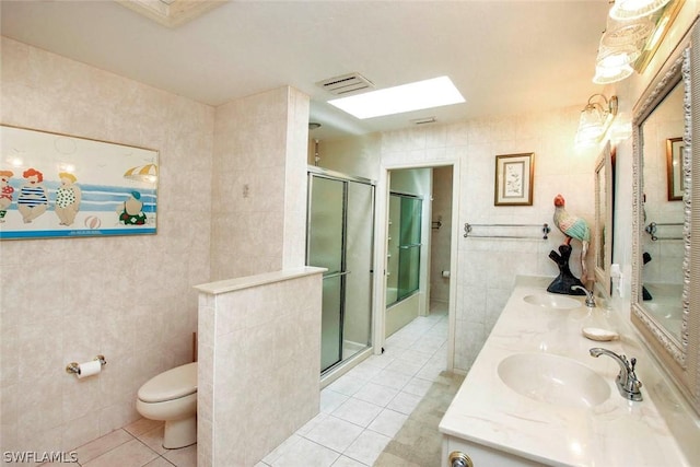 bathroom with tile patterned flooring, visible vents, a shower stall, tile walls, and a sink