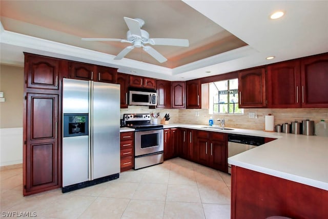 kitchen with dark brown cabinets, light countertops, stainless steel appliances, a raised ceiling, and a sink