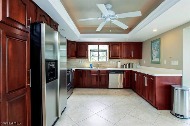 kitchen with a sink, a raised ceiling, light countertops, and stainless steel appliances