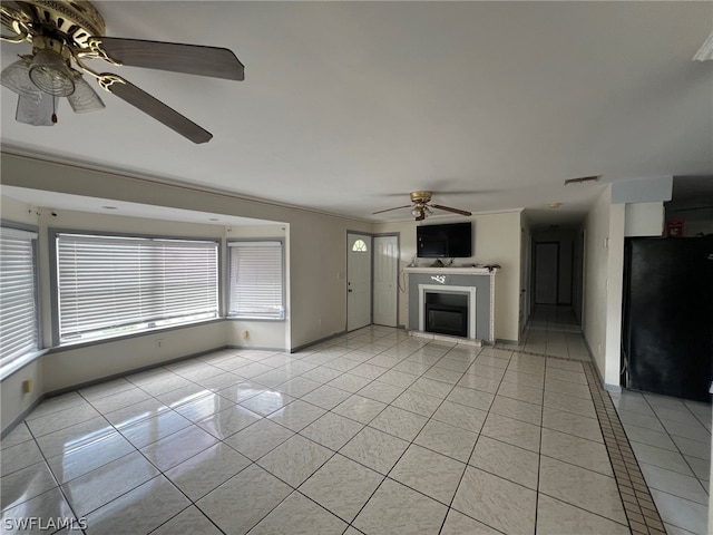 unfurnished living room with ceiling fan, light tile flooring, and ornamental molding