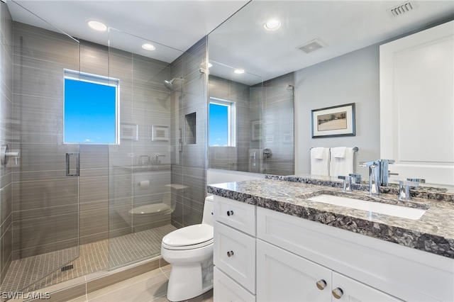 bathroom with vanity, a healthy amount of sunlight, an enclosed shower, and toilet