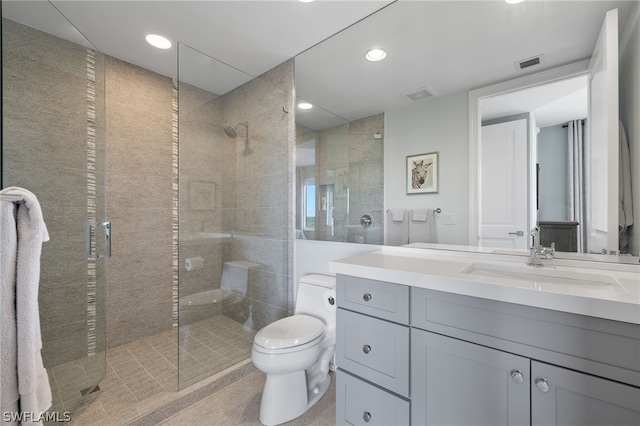 bathroom featuring visible vents, a tile shower, vanity, and toilet