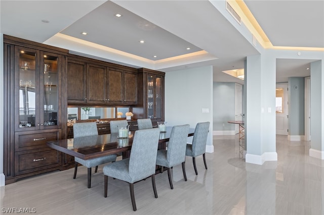 dining room with baseboards, a raised ceiling, and recessed lighting