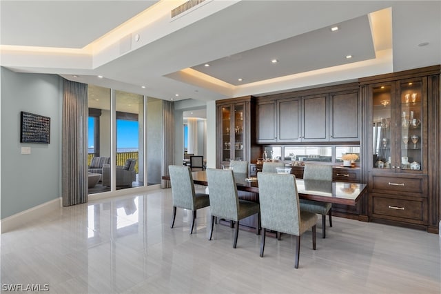 dining area with a tray ceiling, visible vents, baseboards, and recessed lighting