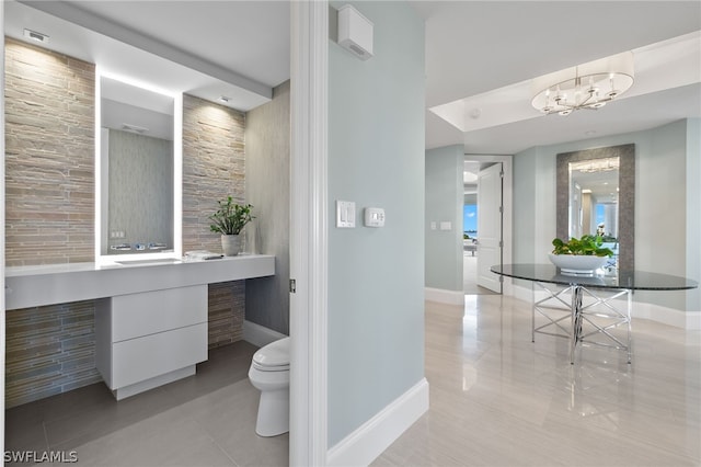 bathroom with toilet, vanity, a chandelier, tile patterned flooring, and baseboards