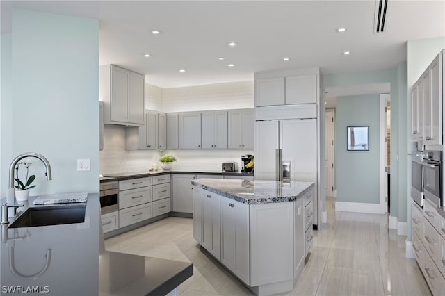 kitchen with stainless steel oven, a center island, sink, and decorative backsplash