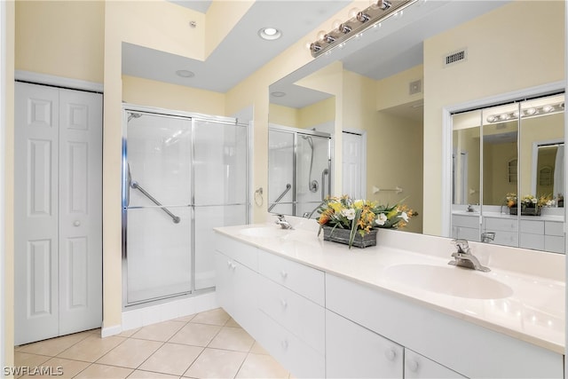 bathroom featuring dual vanity, tile floors, and a shower with door