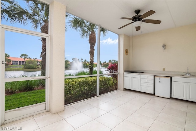 interior space with an outdoor kitchen, ceiling fan, sink, and a water view