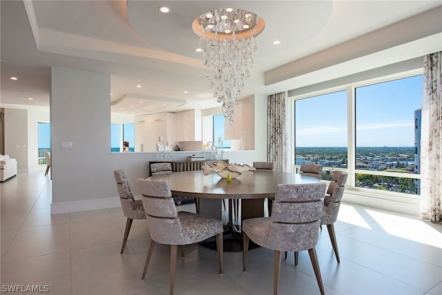 tiled dining space with plenty of natural light, a notable chandelier, and a raised ceiling