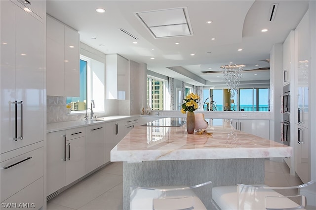 kitchen with white cabinets, a kitchen breakfast bar, a kitchen island, and light stone counters