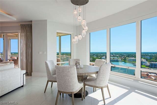 dining area with light tile flooring and a water view