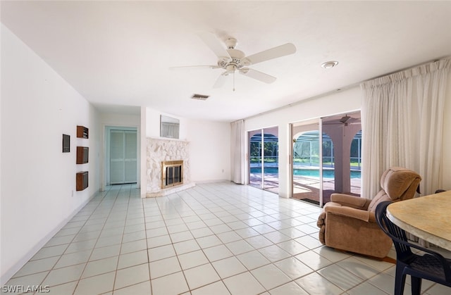 tiled living room featuring ceiling fan and a fireplace