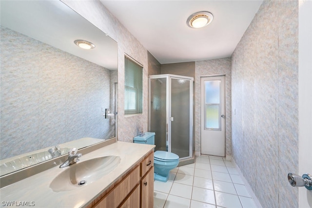 bathroom featuring tile floors, toilet, a shower with shower door, and vanity with extensive cabinet space