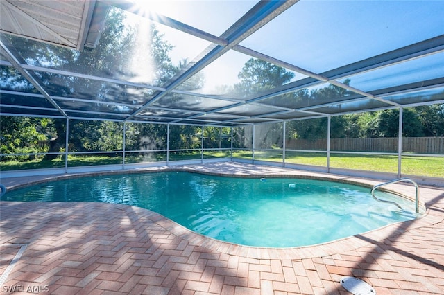 view of pool with glass enclosure, a yard, and a patio