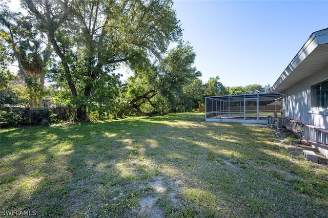 view of yard with a pool and glass enclosure