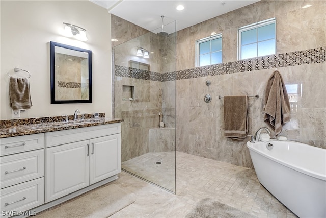 bathroom featuring vanity, independent shower and bath, and tile walls