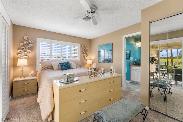 carpeted bedroom featuring a textured ceiling, ceiling fan, a closet, and ensuite bath