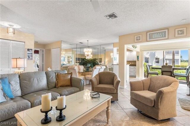 living room featuring a textured ceiling, light tile patterned floors, visible vents, and an inviting chandelier