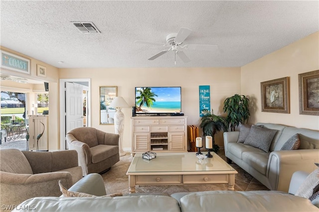 living room featuring visible vents, ceiling fan, and a textured ceiling