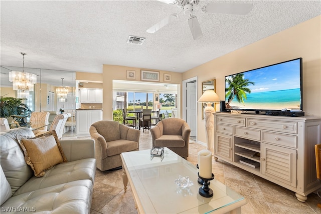 living room with ceiling fan with notable chandelier and a textured ceiling