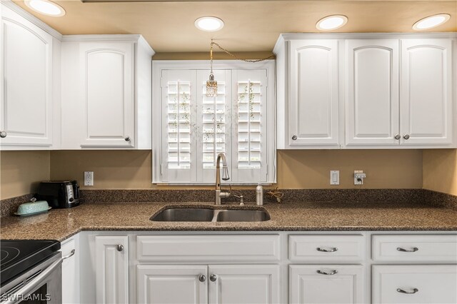 kitchen with sink, dark stone countertops, and white cabinetry