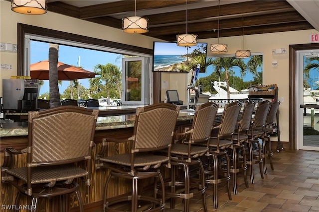 bar with stone finish floor, beam ceiling, and decorative light fixtures