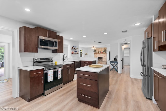 kitchen featuring a peninsula, visible vents, open floor plan, light countertops, and appliances with stainless steel finishes