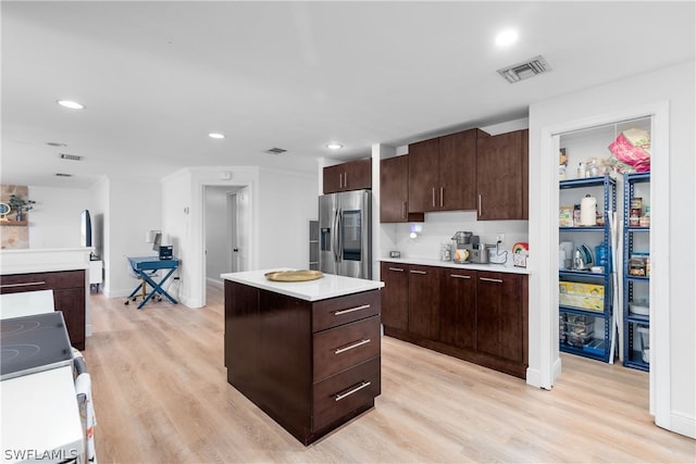 kitchen with visible vents, electric stove, a center island, light countertops, and stainless steel refrigerator with ice dispenser