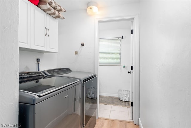 laundry room with cabinet space, light tile patterned floors, and separate washer and dryer