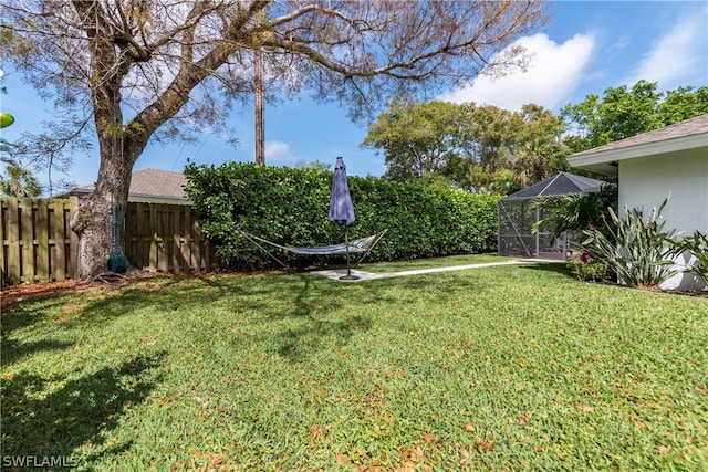 view of yard with glass enclosure and fence