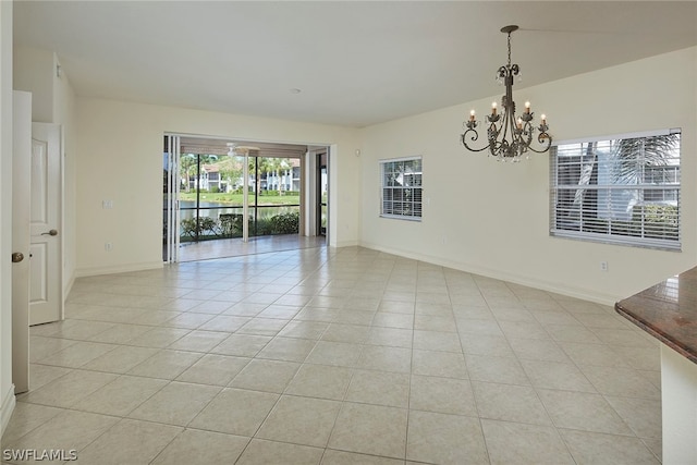 spare room with light tile flooring and a notable chandelier