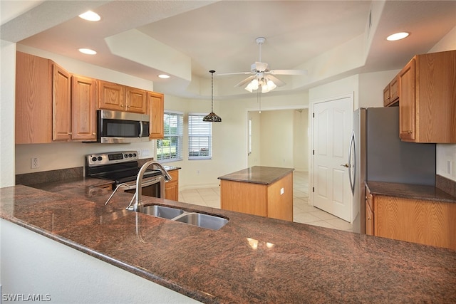 kitchen with light tile flooring, a tray ceiling, stainless steel appliances, and ceiling fan