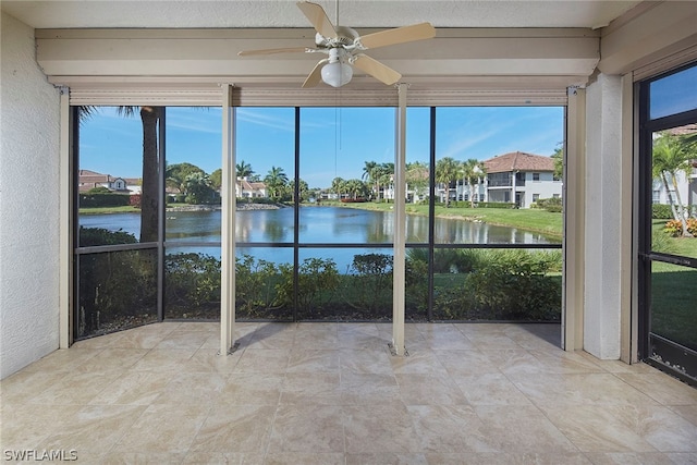 unfurnished sunroom featuring ceiling fan, a healthy amount of sunlight, and a water view