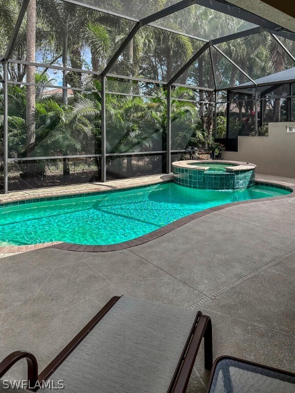 view of swimming pool with an in ground hot tub, a patio area, and a lanai