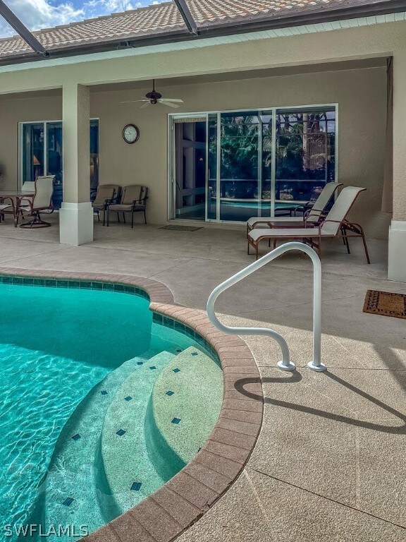 view of pool featuring a patio, ceiling fan, and glass enclosure