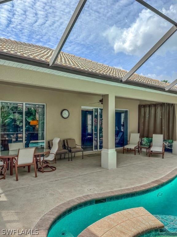 rear view of property with a patio, ceiling fan, and glass enclosure