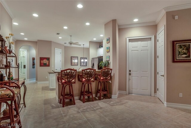 kitchen featuring ornamental molding, stainless steel fridge, light tile patterned floors, white cabinets, and ceiling fan