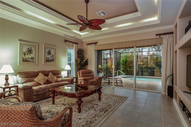 living room with ornamental molding, light tile patterned flooring, a raised ceiling, and ceiling fan