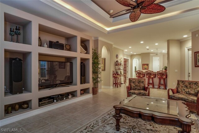 living room with ornamental molding, tile patterned flooring, ceiling fan, and built in shelves