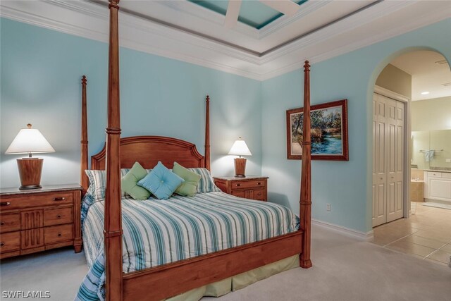 carpeted bedroom featuring a closet, ensuite bath, and ornamental molding