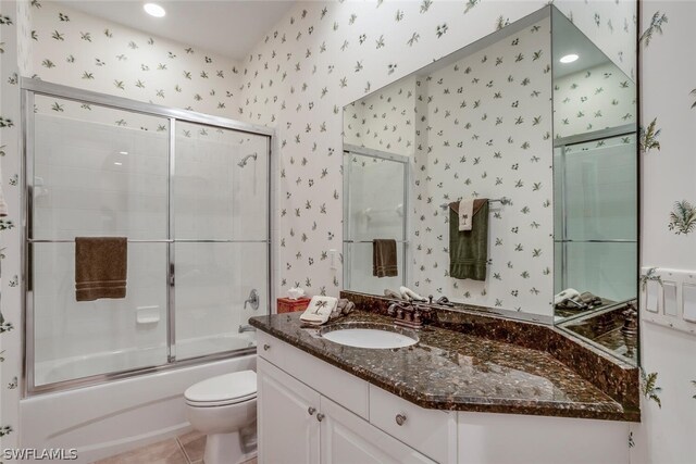 full bathroom featuring vanity, enclosed tub / shower combo, toilet, and tile patterned flooring