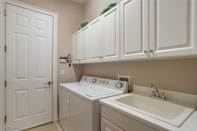 laundry room with sink, light tile patterned flooring, washing machine and dryer, and cabinets