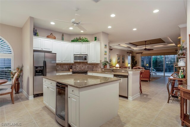 kitchen featuring a kitchen island, kitchen peninsula, white cabinetry, stainless steel appliances, and wine cooler